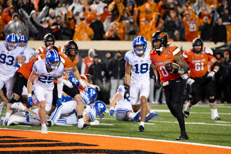 Oklahoma State running back Ollie Gordon II (0) runs past BYU linebacker Ace Kaufusi (18) and s ...