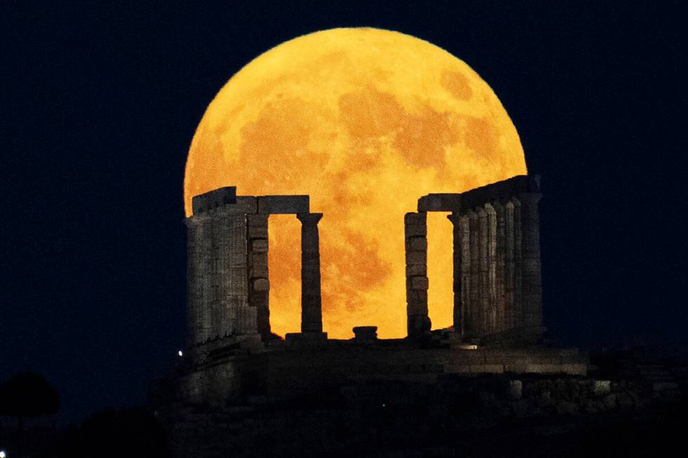 The super moon rises behind the Temple of Poseidon at Cape Sounio, south of Athens, Monday, Aug ...