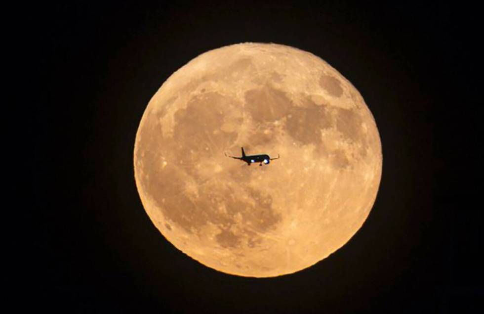 With the blue moon behind its tail, a jetliner lands in Las Vegas, Monday. Aug. 19, 2024. (Chas ...