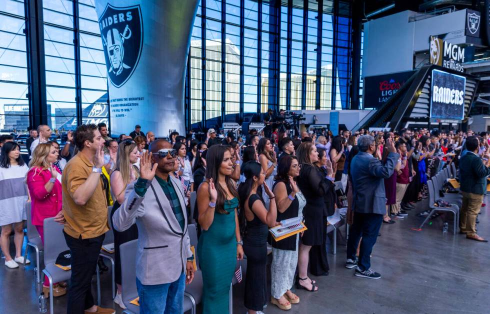 Candidates raise their hands for the Oath of Allegiance during a naturalization ceremony at All ...