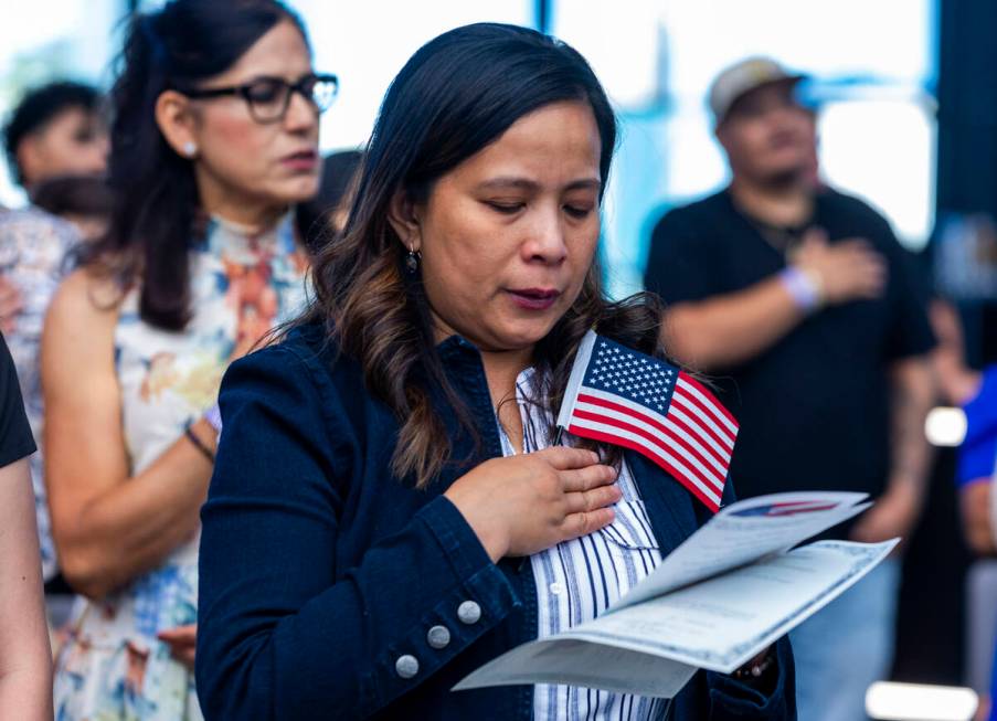 Candidate Rosalyn Tuggle stands with others for the Pledge of Allegiance during a naturalizatio ...