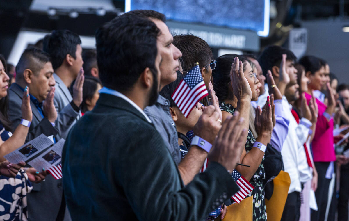 Candidates raise their hands for the Oath of Allegiance during a naturalization ceremony at All ...