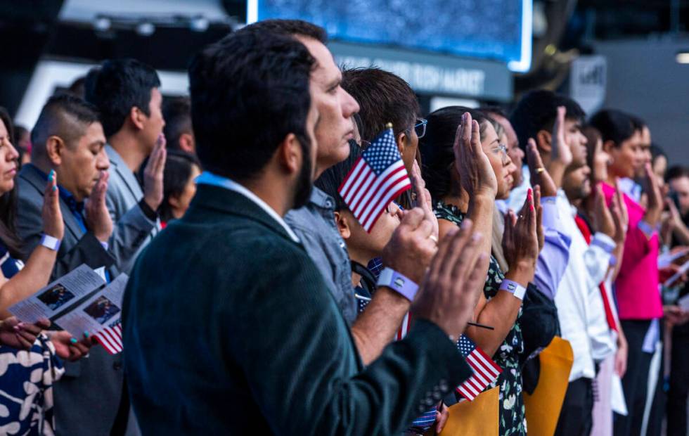 Candidates raise their hands for the Oath of Allegiance during a naturalization ceremony at All ...