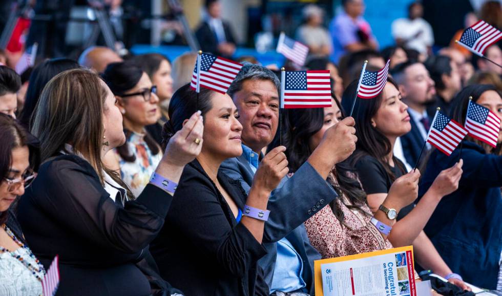 New citizens wave flags during a naturalization ceremony at Allegiant Stadium on Tuesday, Aug. ...