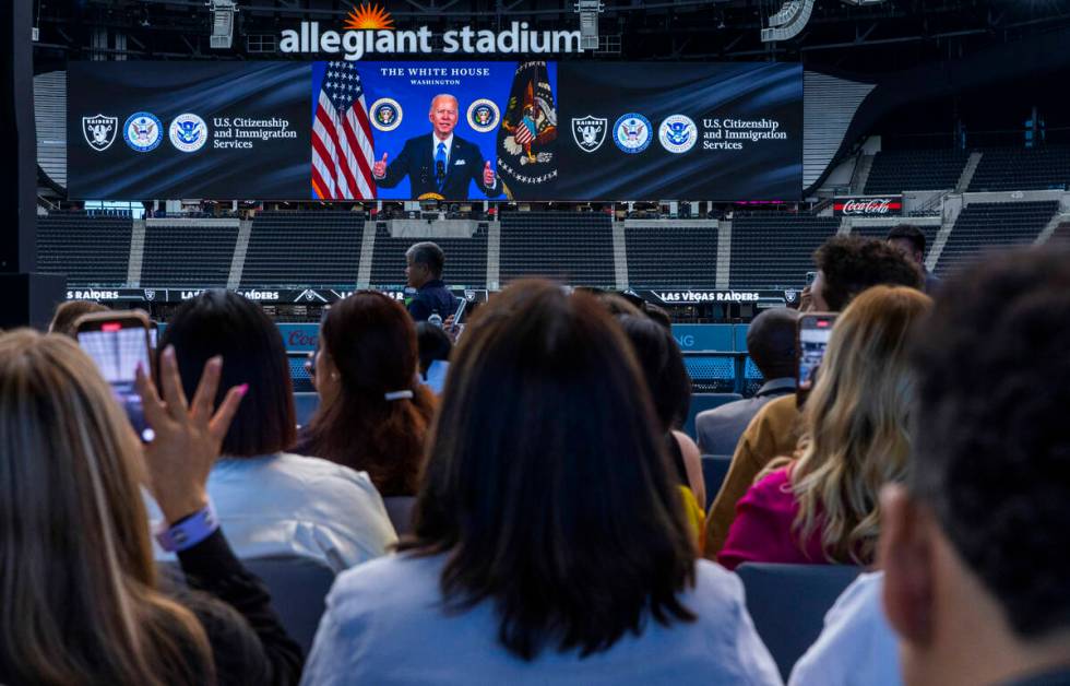 President Joe Biden is broadcast on a message to the new citizens during a naturalization cerem ...