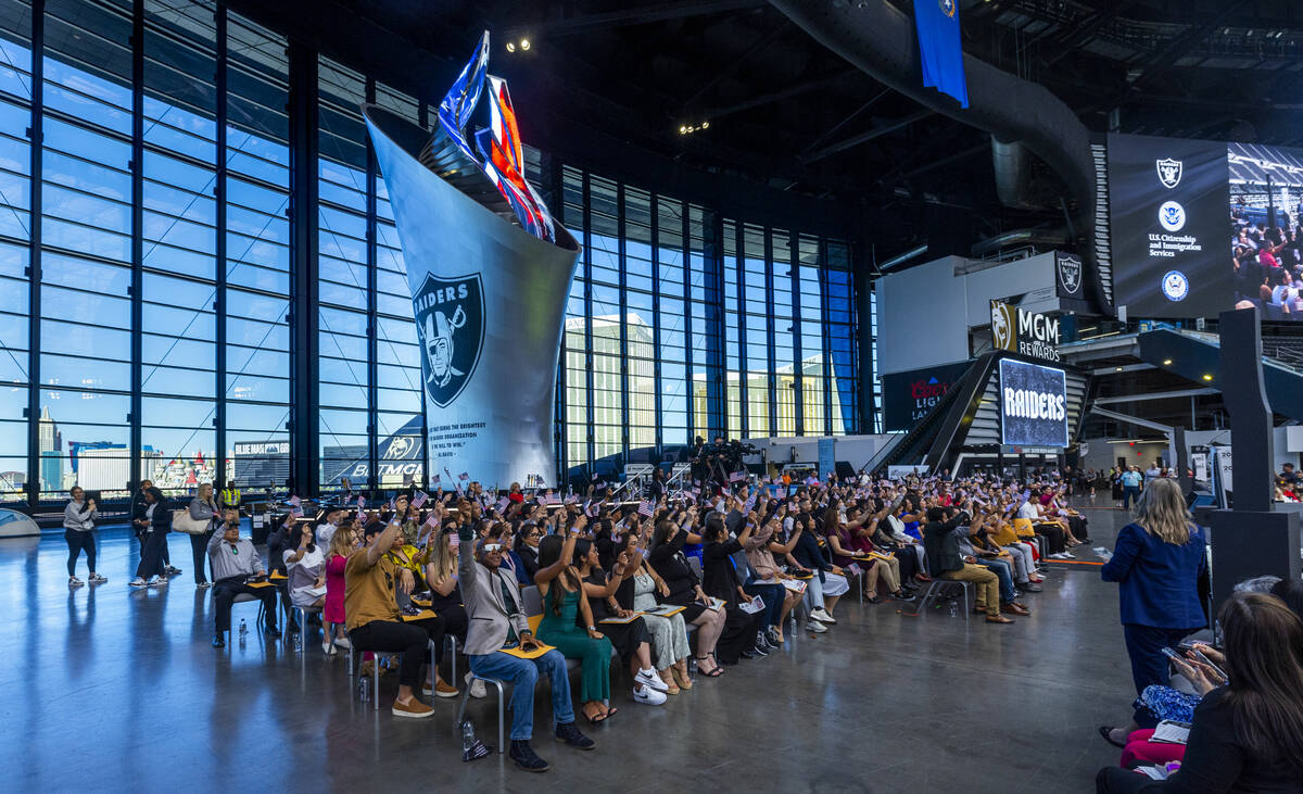 New citizens wave flags as the Al Davis Memorial Torch is lit during a naturalization ceremony ...