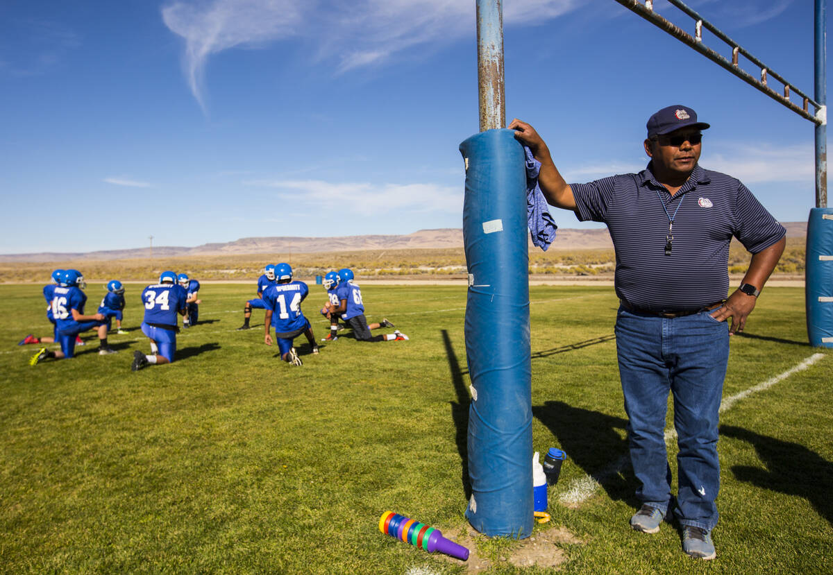 McDermitt football coach Richard Egan, right, looks on as his players stretch during practice a ...