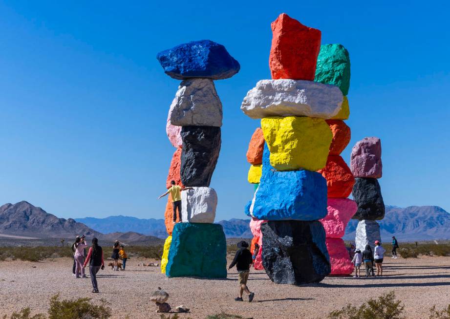 A visitor stands atop of one of the rocks as he and others stop by to see the Seven Magic Mount ...