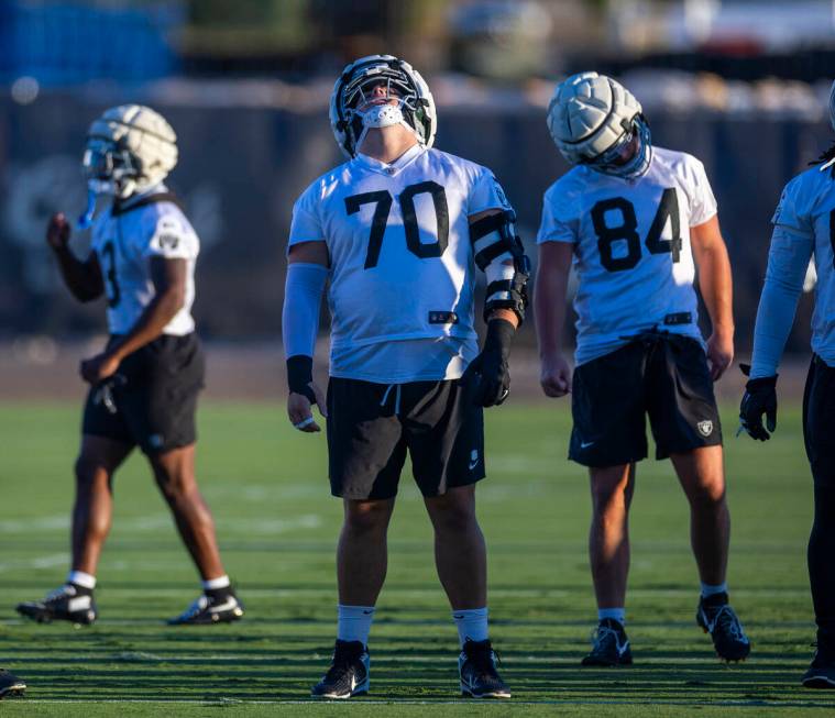 Raiders guard Jackson Powers-Johnson (70) and teammates do neck rolls while stretching during p ...