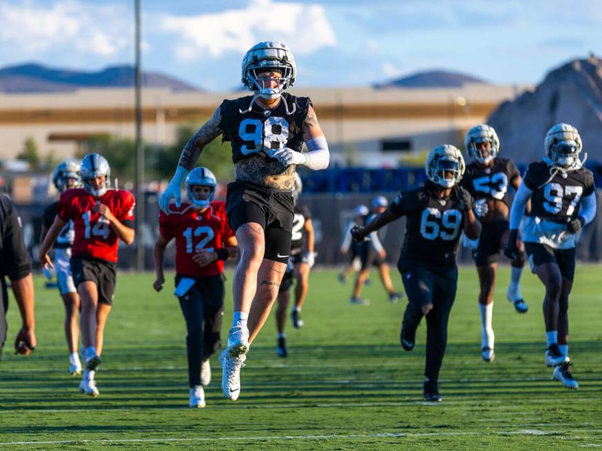 Raiders defensive end Maxx Crosby (98) catches some air during warm ups at practice in the Inte ...