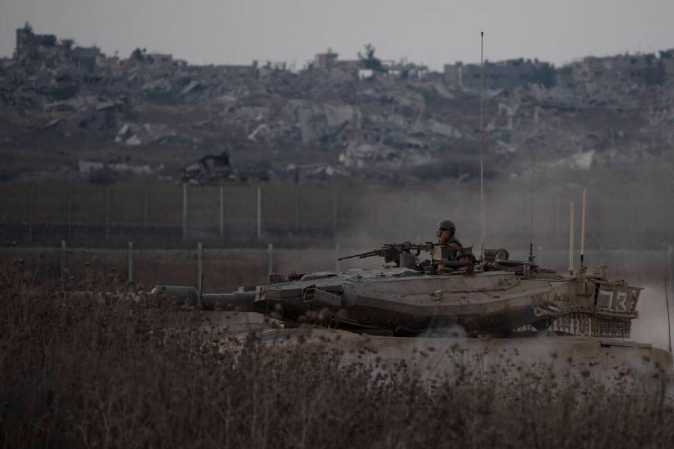 Israeli soldiers move on the top of a tank near the Israeli-Gaza border, as seen from southern ...