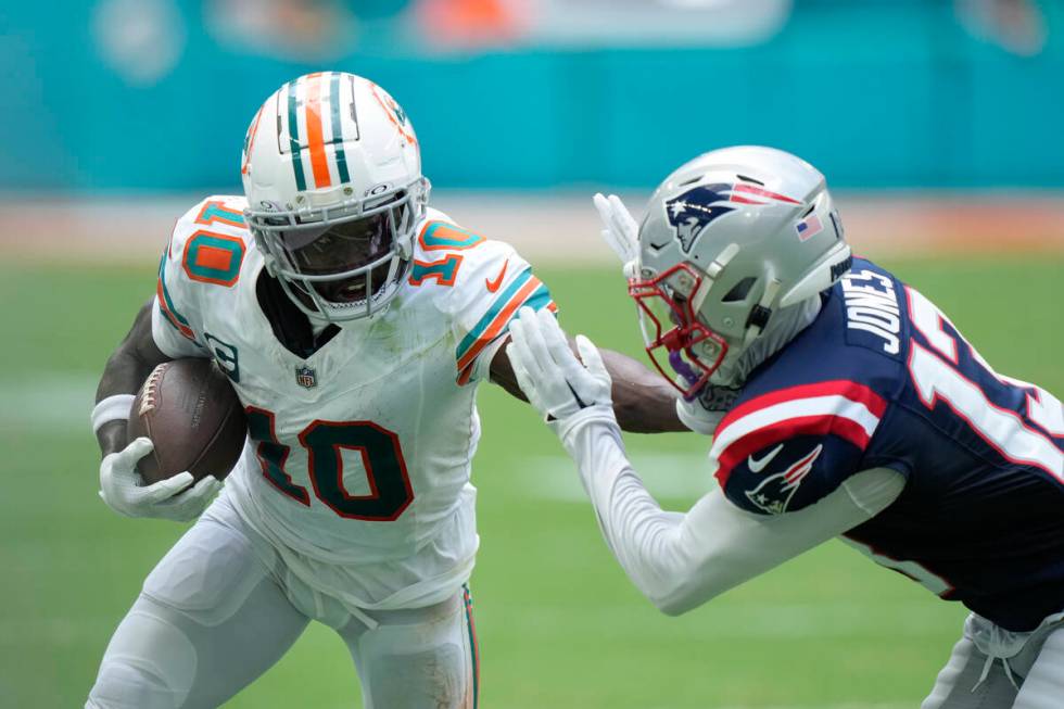 Miami Dolphins wide receiver Tyreek Hill (10) holds off New England Patriots cornerback Jack Jo ...