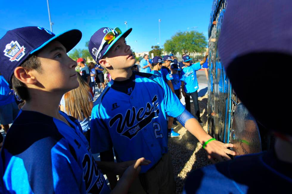 Mountain Ridge Little Leauge player Austin Kryszczuk, center, examines a monument dedicated to ...