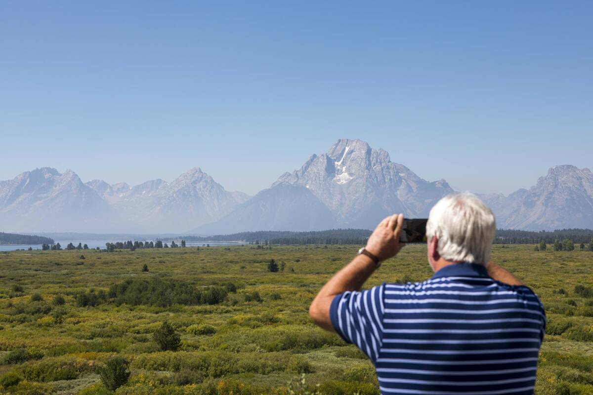 Steve Carringer of Tennessee takes a photo of the mountains at Jackson Lake Lodge, the site of ...