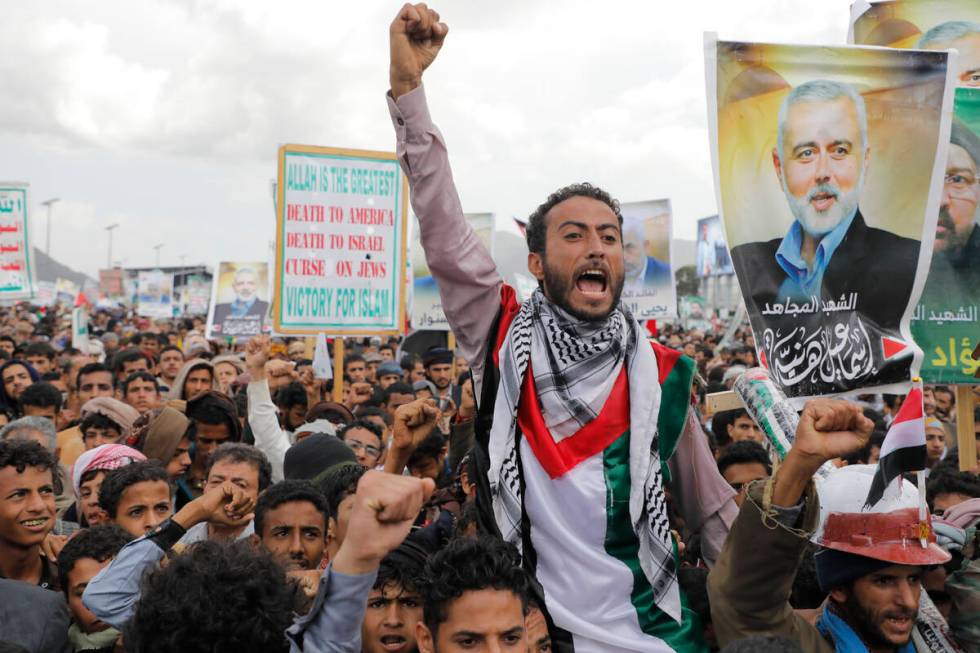 Houthi supporters hold posters showing Ismail Haniyeh, a Hamas leader recently assassinated in ...