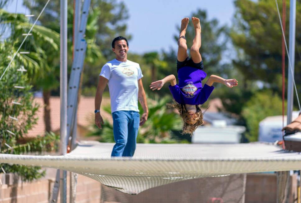 Renato Fernandes watches as his daughter Katalina does a backflip on the netting of their backy ...