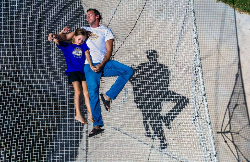 Renato Fernandes with his daughter Katalina relax atop of the netting on their backyard trapeze ...