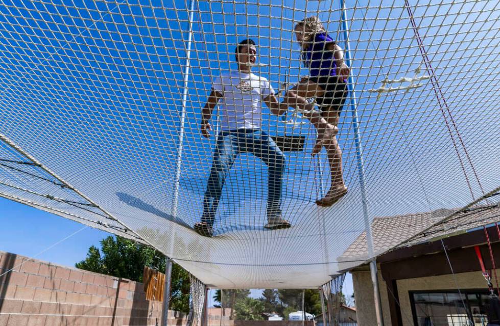 Renato Fernandes with his daughter Katalina atop of the netting on their backyard trapeze on Sa ...