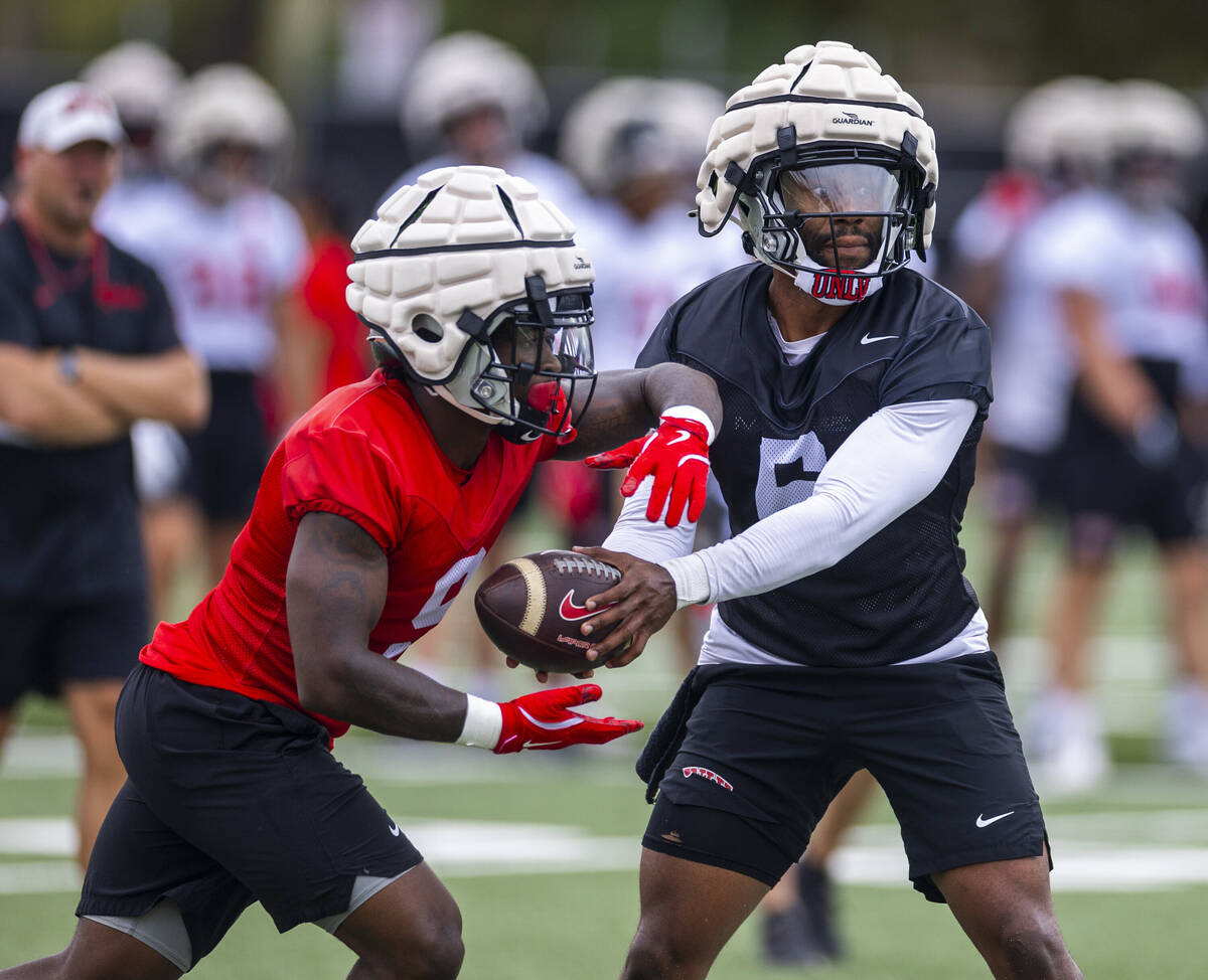 UNLV quarterback Hajj-Malik Williams (6) hands the ball off to running back Jai'Den Thomas (9) ...