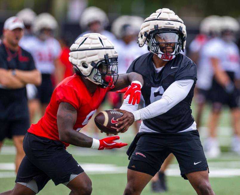 UNLV quarterback Hajj-Malik Williams (6) hands the ball off to running back Jai'Den Thomas (9) ...