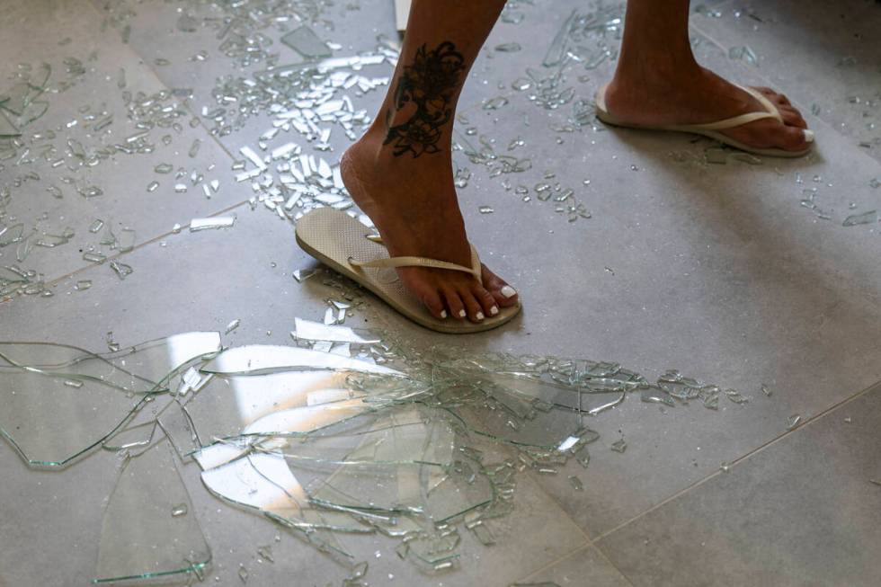 A woman stands on broken glass from the window in her bedroom following an attack from Lebanon, ...