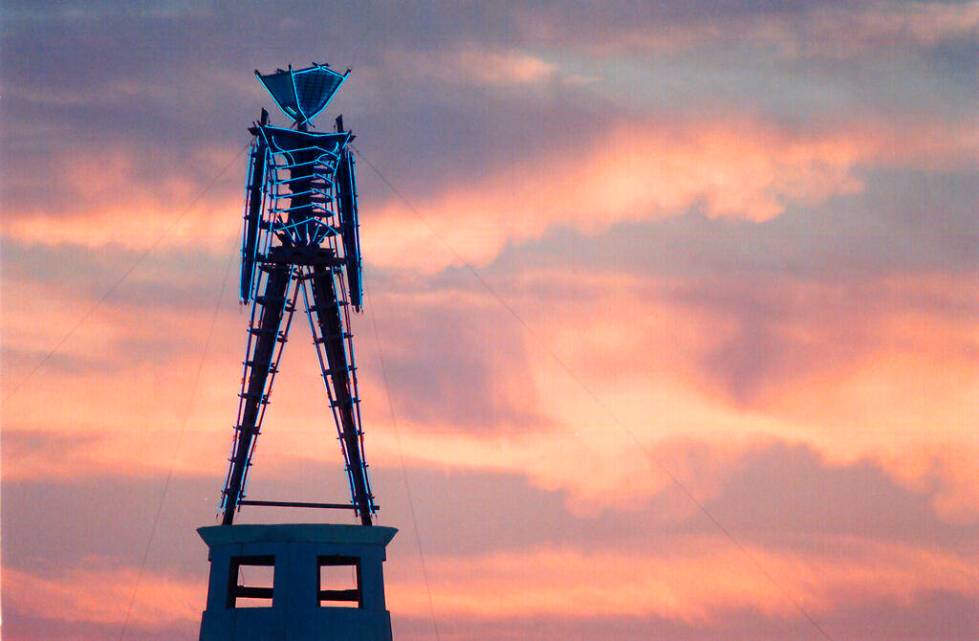 FILE - In this Aug. 26, 2002 file photo the sun rises behind a wood and neon statue, the center ...