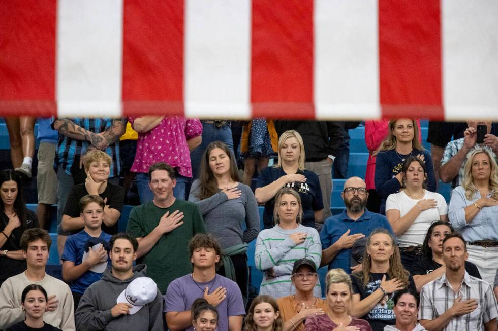 Spectators place their hands on their chests as the national anthem is sung before the volleyba ...