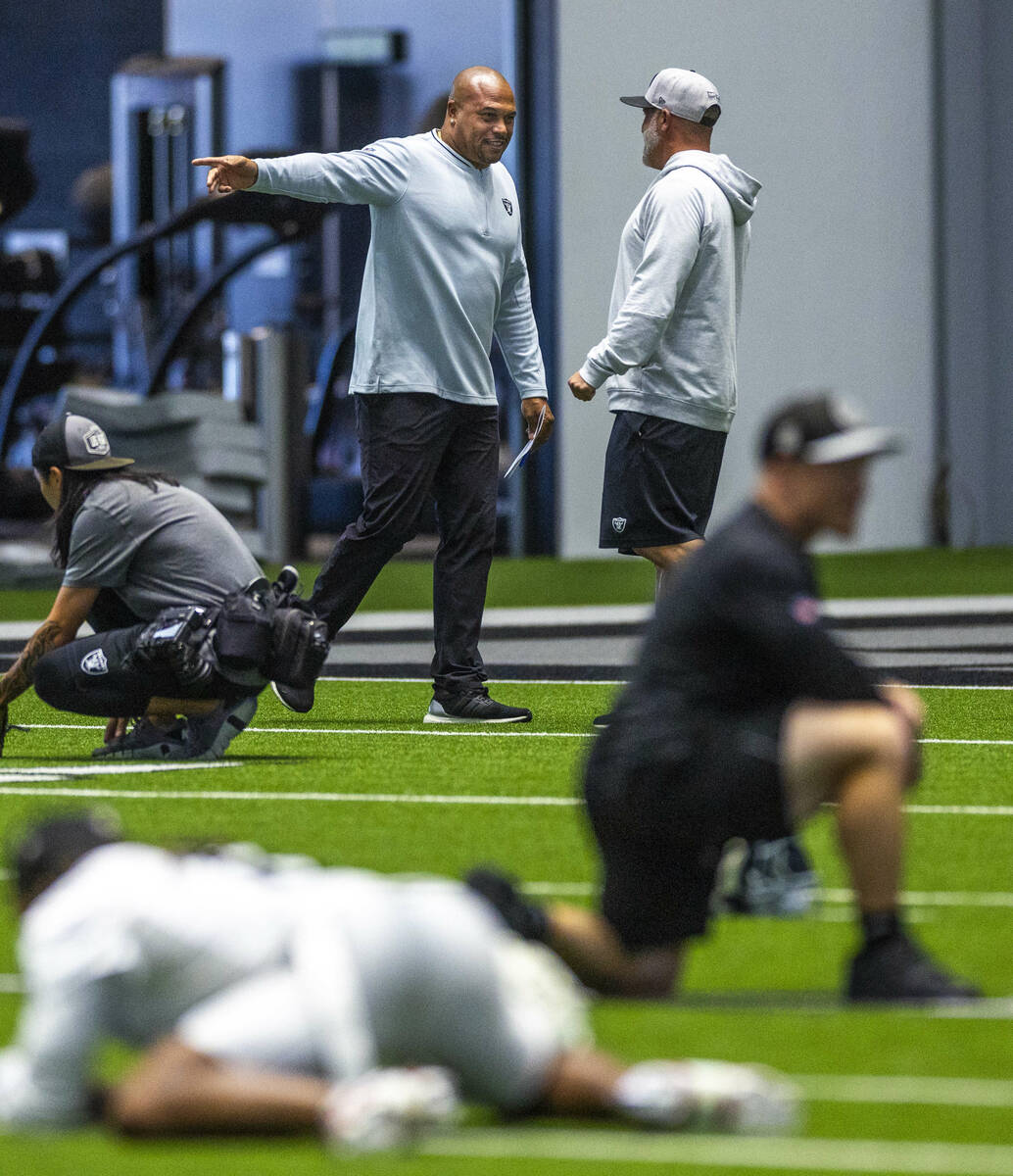 Raiders head coach Antonio Pierce chats with another coach during practice at the Intermountain ...