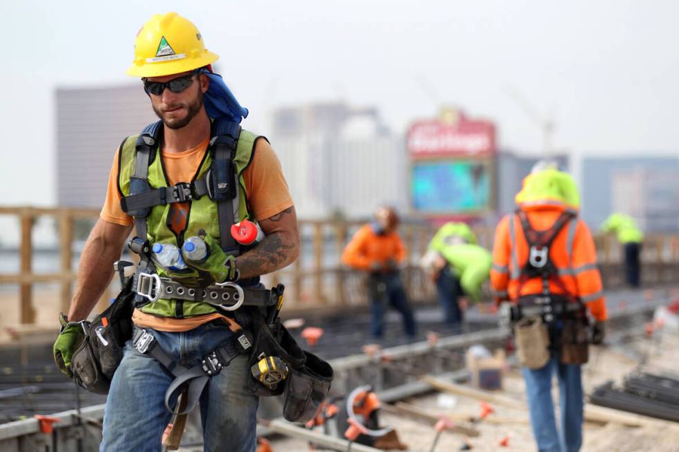 A worker grabs bottles of water while working on the Nevada Department of Transportation's Proj ...