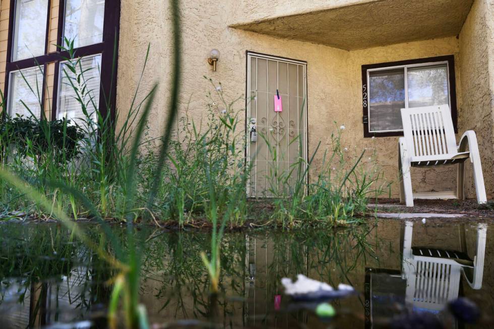 Water pools near a townhome with a notice from the city taped to a door in Somerset Park in Hen ...