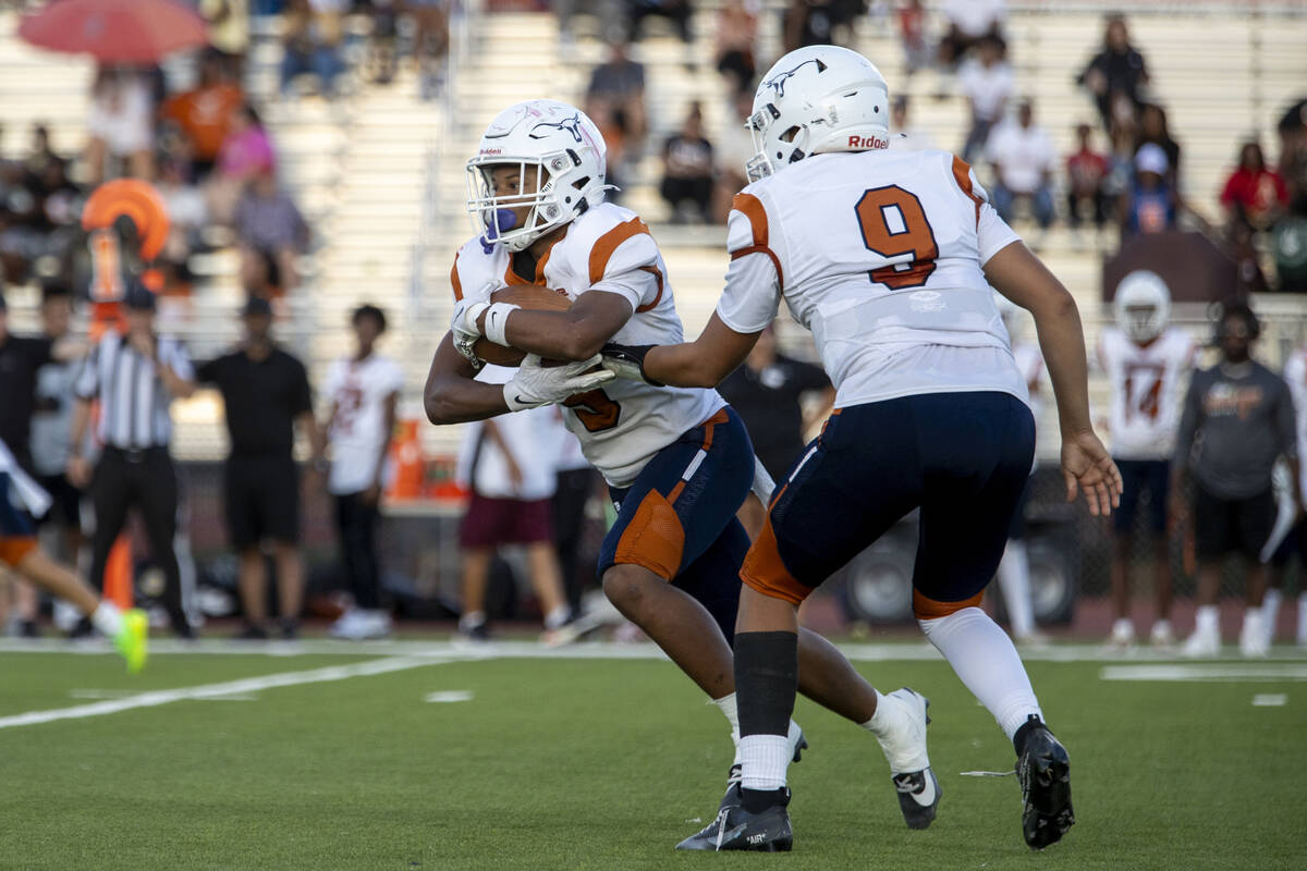 Legacy quarterback Aidan Crawford (9) hands the ball to halfback Zaione Henderson (5) during th ...