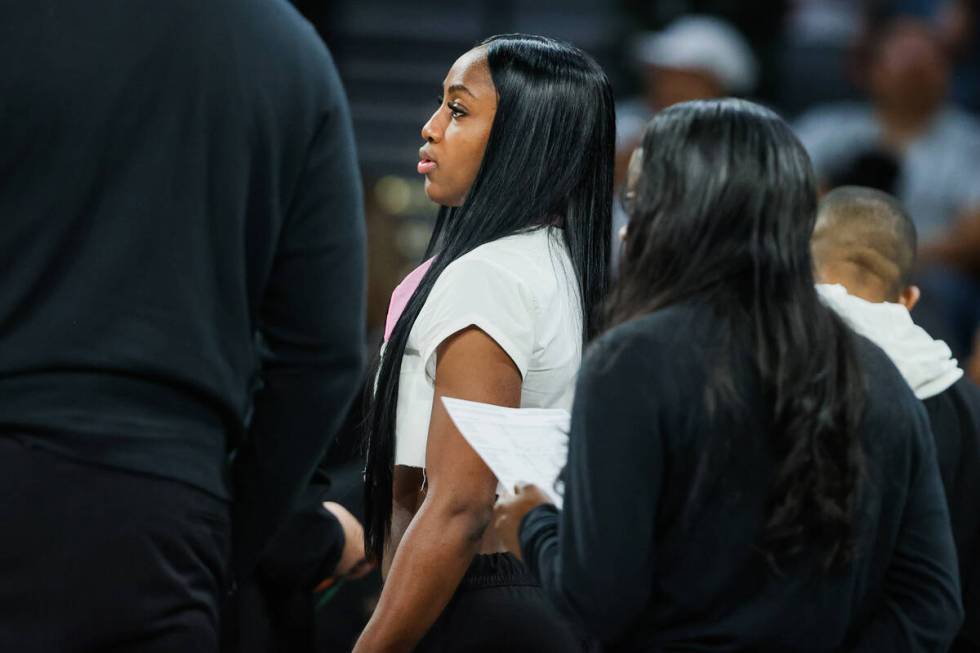 Aces guard Jackie Young is seen on the sidelines in street clothes during a WNBA basketball gam ...