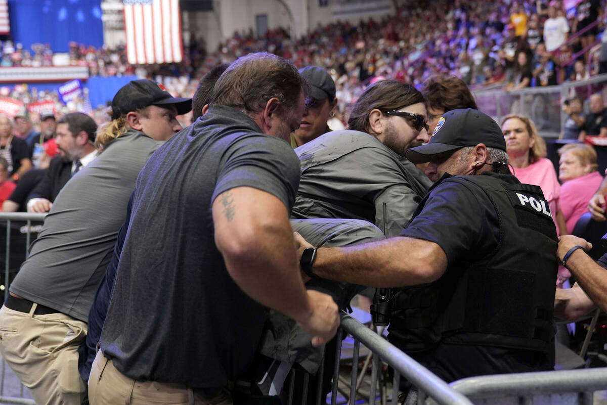 Police remove a man, center with sunglasses, who had climbed onto the media riser, as Republica ...