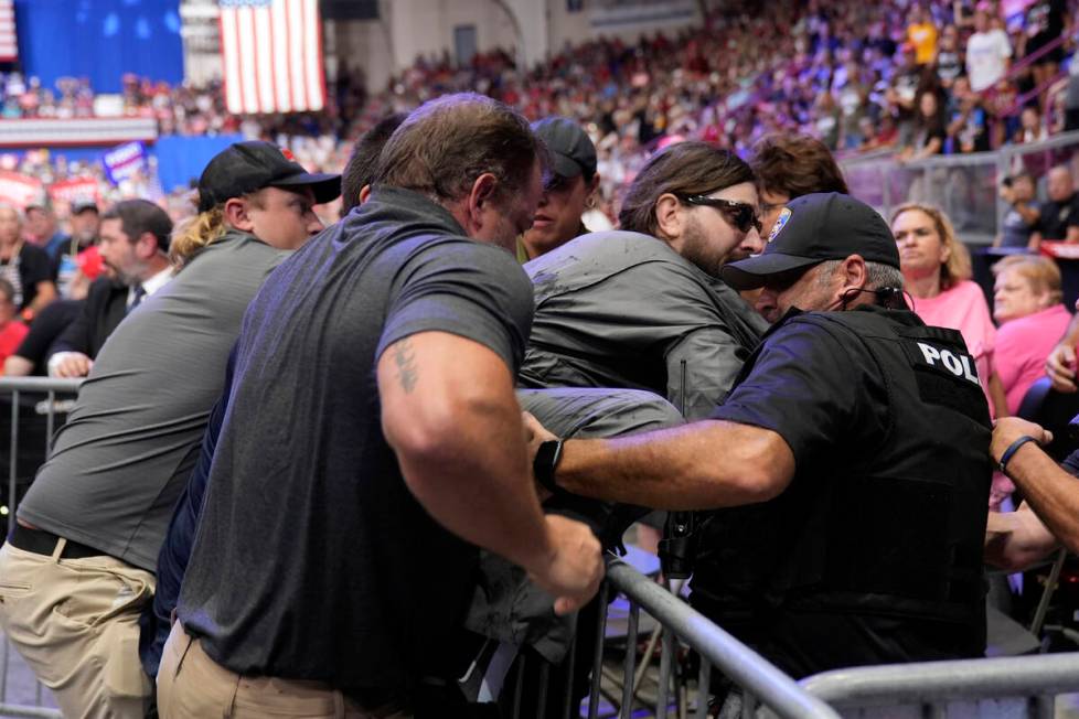 Police remove a man, center with sunglasses, who had climbed onto the media riser, as Republica ...