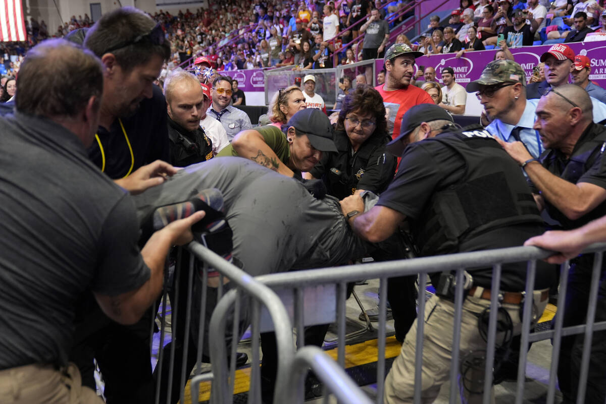 Police remove a man, center, who had climbed over barricades and onto the media riser, as Repub ...