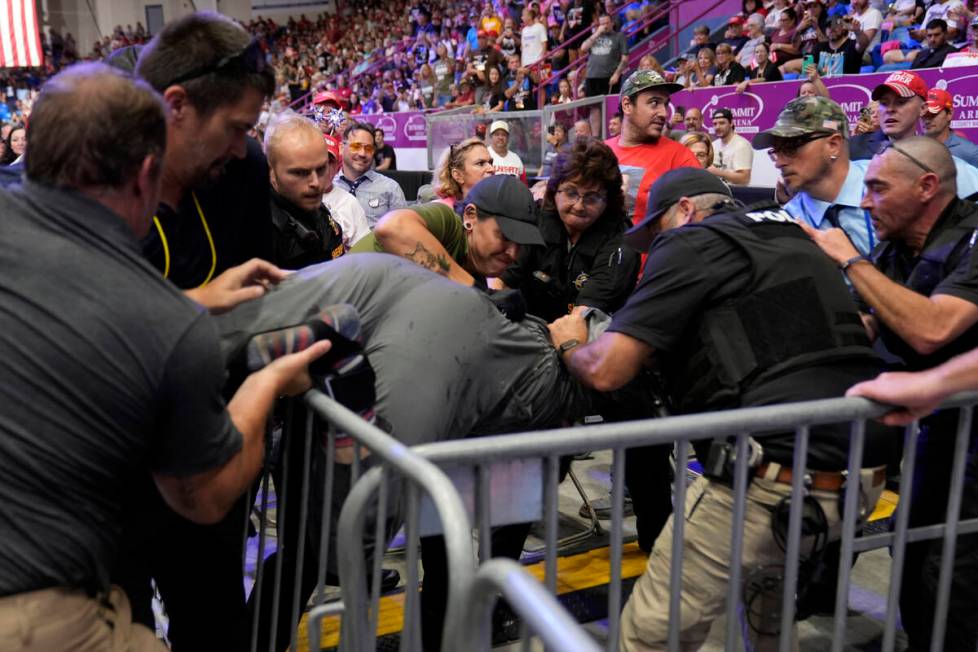 Police remove a man, center, who had climbed over barricades and onto the media riser, as Repub ...