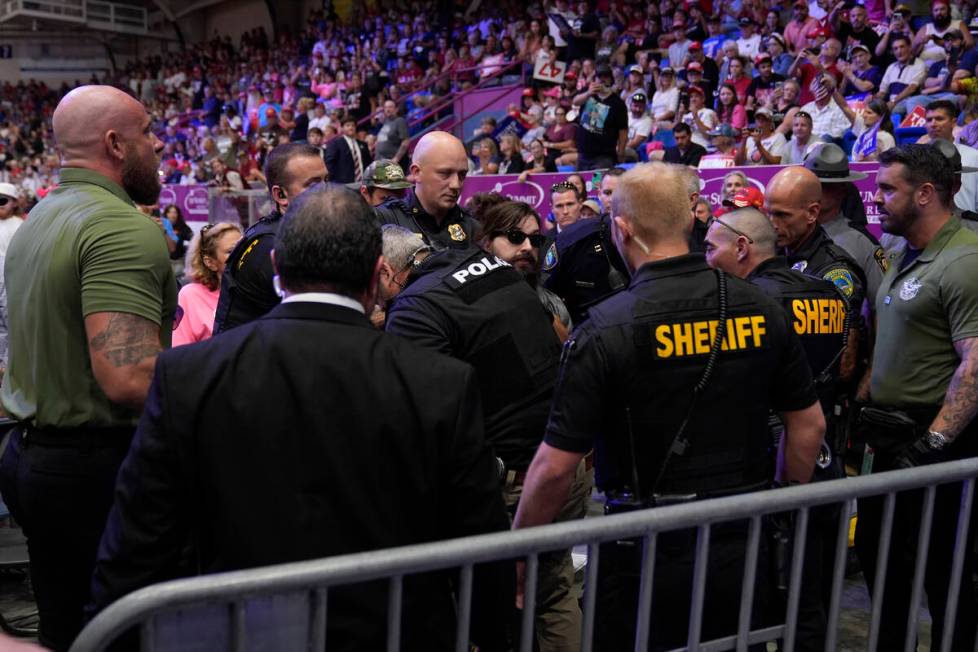 Police remove a man, center with sunglasses, who had climbed onto the media riser, as Republica ...