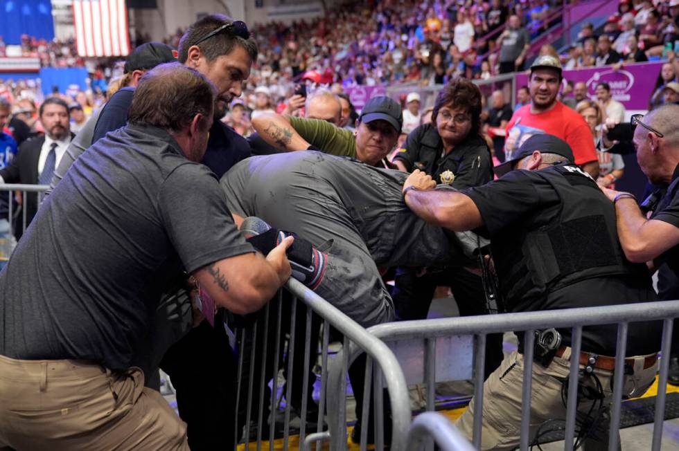 Police remove a man, center, who had climbed onto the media riser, as Republican presidential n ...