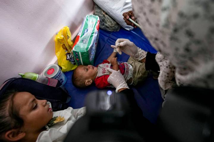 A health worker administers a polio vaccine to a child at a hospital in Khan Younis, Saturday, ...