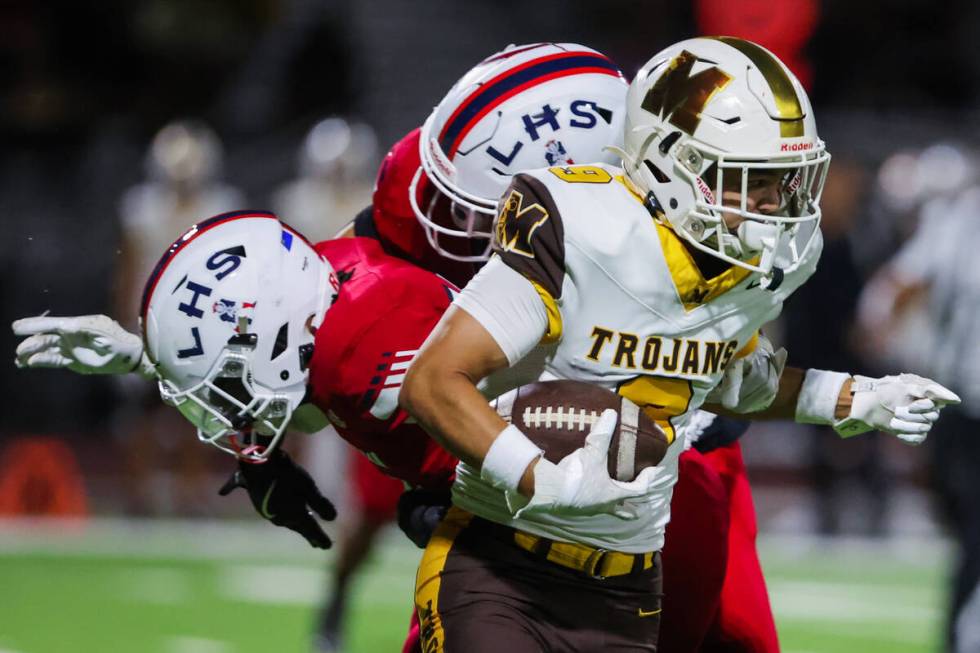 Mililani defensive back Kayden Thomas Anzaldo (9) runs the ball past Liberty defenders during a ...