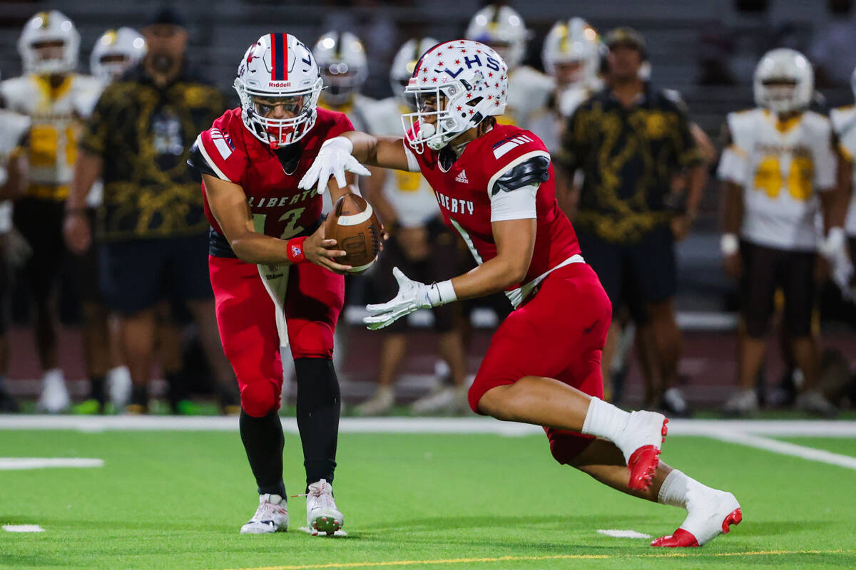 Liberty running back Ezra Sanelivi (1) receives the ball from quarterback Elijah Espinoza (12) ...