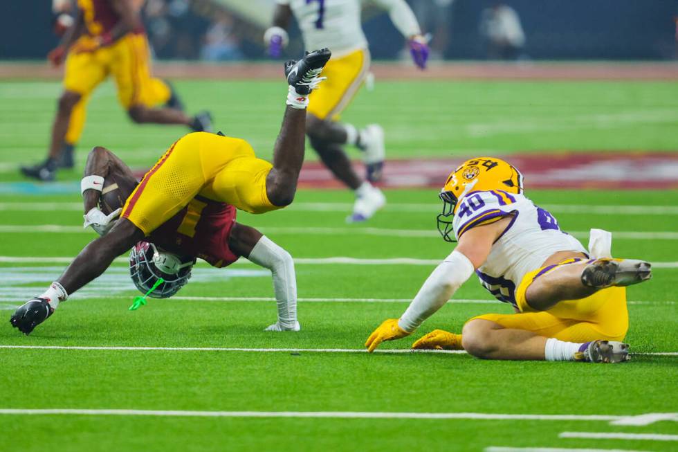 Southern California wide receiver Zachariah Branch (1) tumbles over as LSU linebacker Whit Week ...