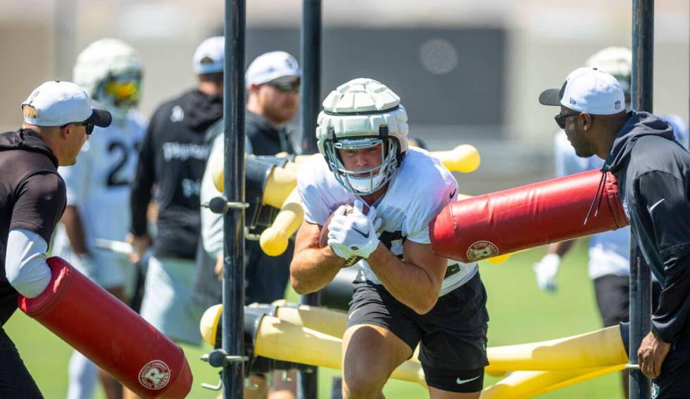 Raiders tight end Brock Bowers (89) takes a hit while running with the ball on a drill during p ...