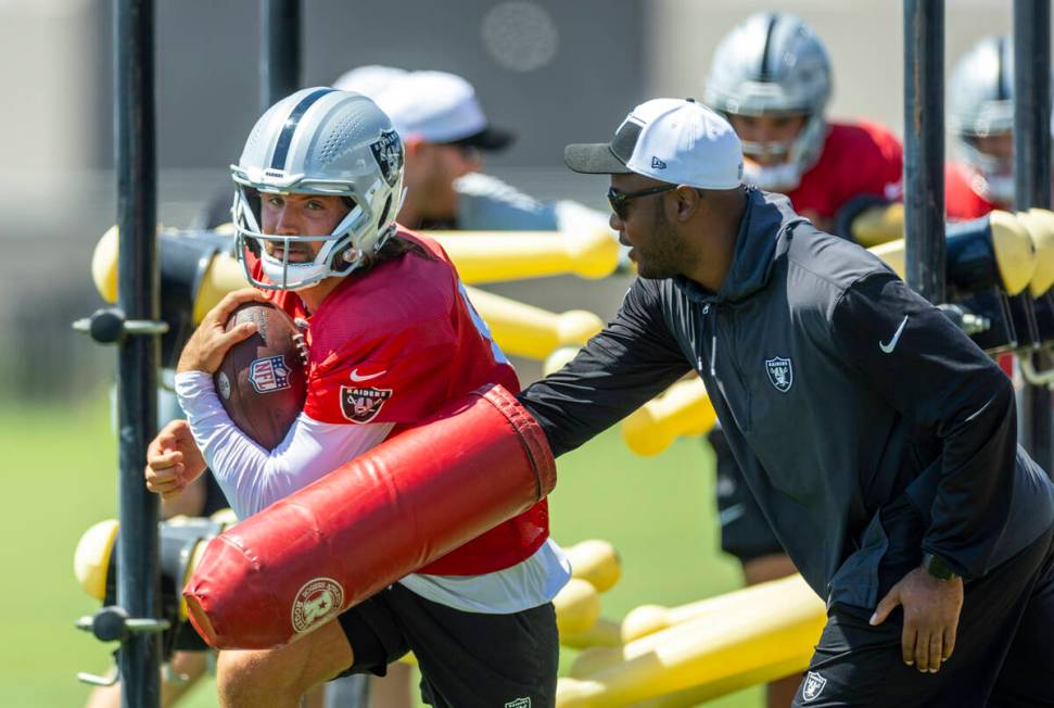 Raiders quarterback Gardner Minshew (15) fights off a swipe at the ball on a run during a drill ...