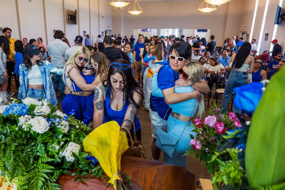 Friends and family members comfort each other and say their final goodbyes during a funeral ser ...