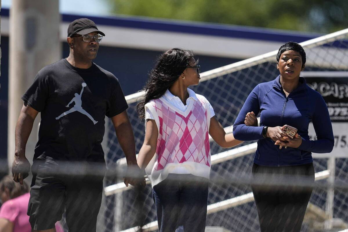 Parents walk their child out of Apalachee High School after a shooting at the school Wednesday, ...