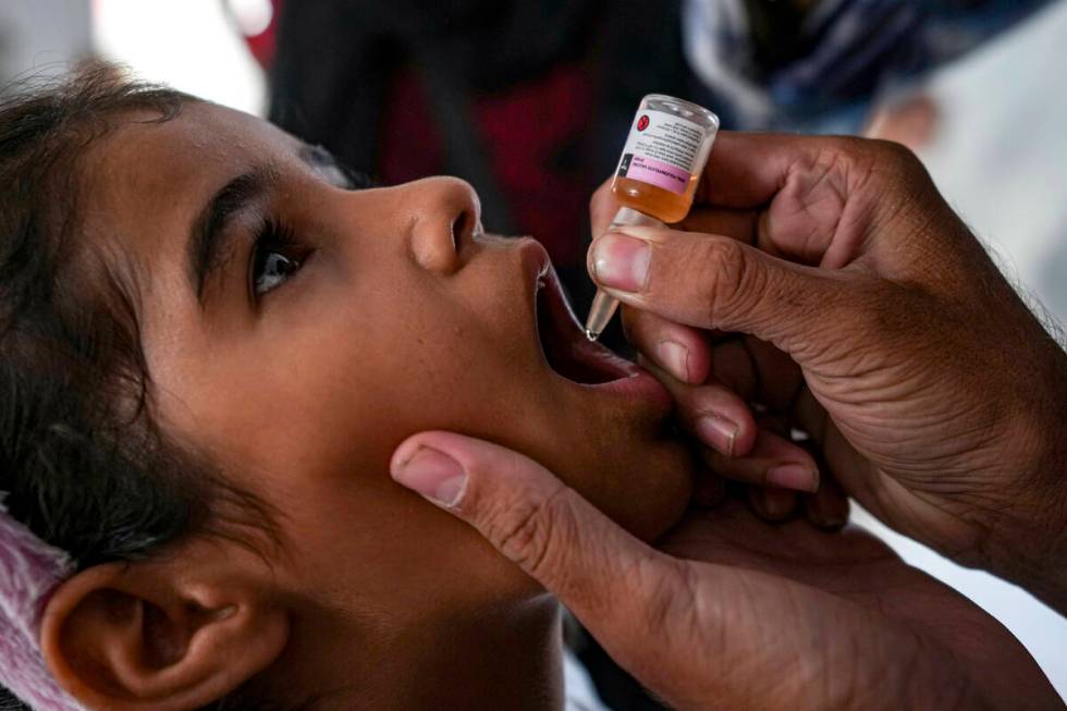 A health worker administers a polio vaccine to a child at a hospital in Deir al-Balah, central ...