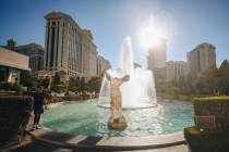 A tourist walks by the Caesars Palace fountains to keep cool as the sun beams down on Sunday, J ...