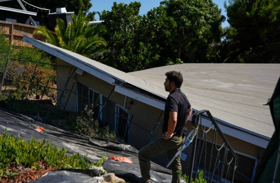 A reporter stands near a home that collapsed due to ongoing landslides in Rancho Palos Verdes, ...