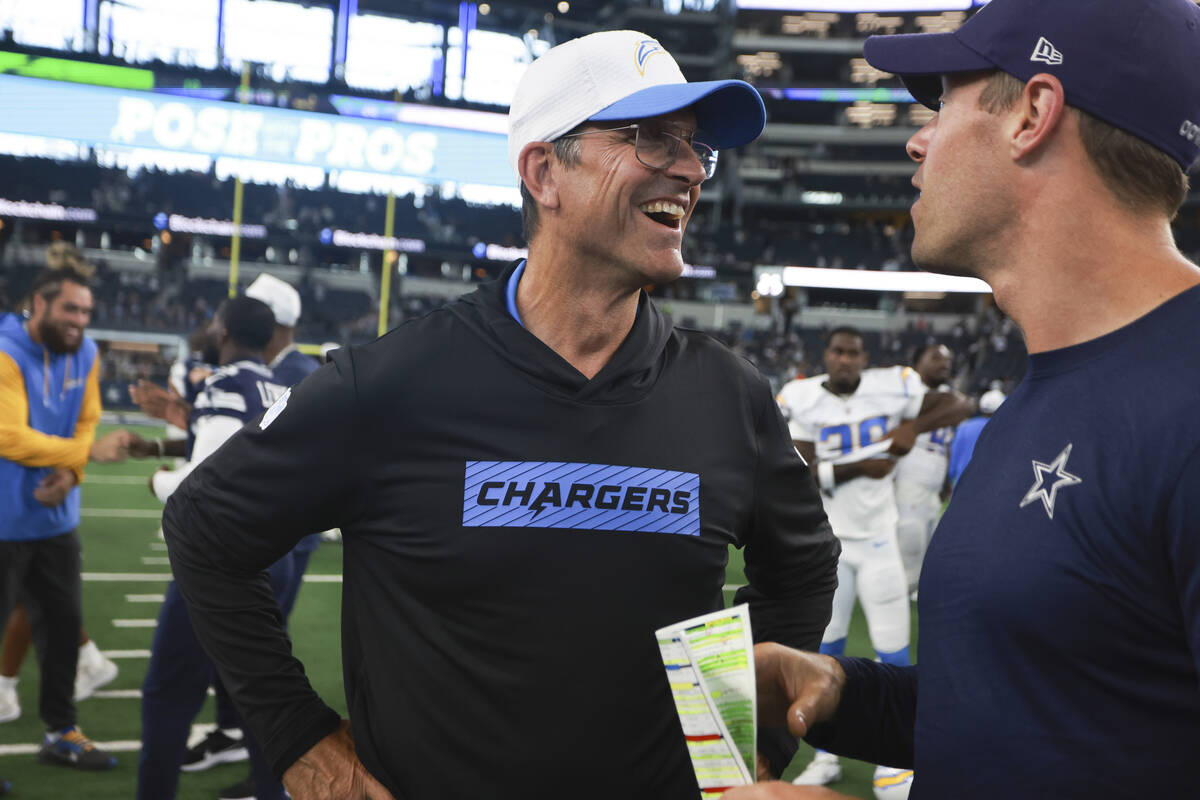 Los Angeles Chargers head coach Jim Harbaugh, center, talks to a member of the Dallas Cowboys c ...